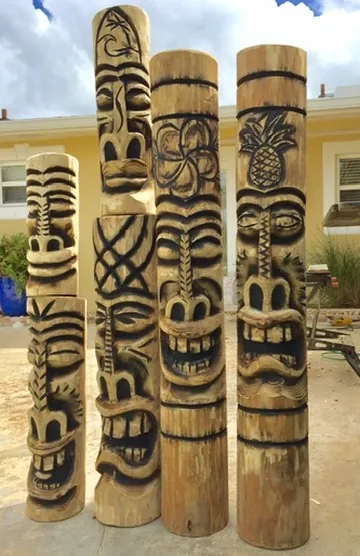Carved wooden tiki posts with faces and tropical motifs