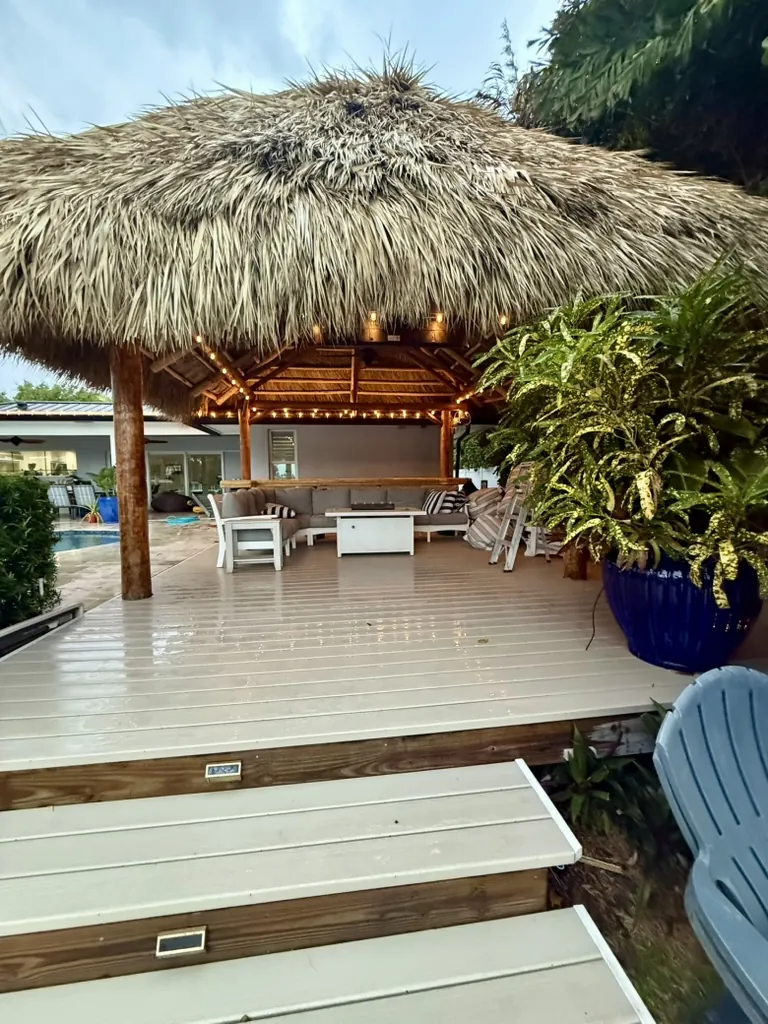 Natural palm tiki hut with a deck, steps and warm string lights
