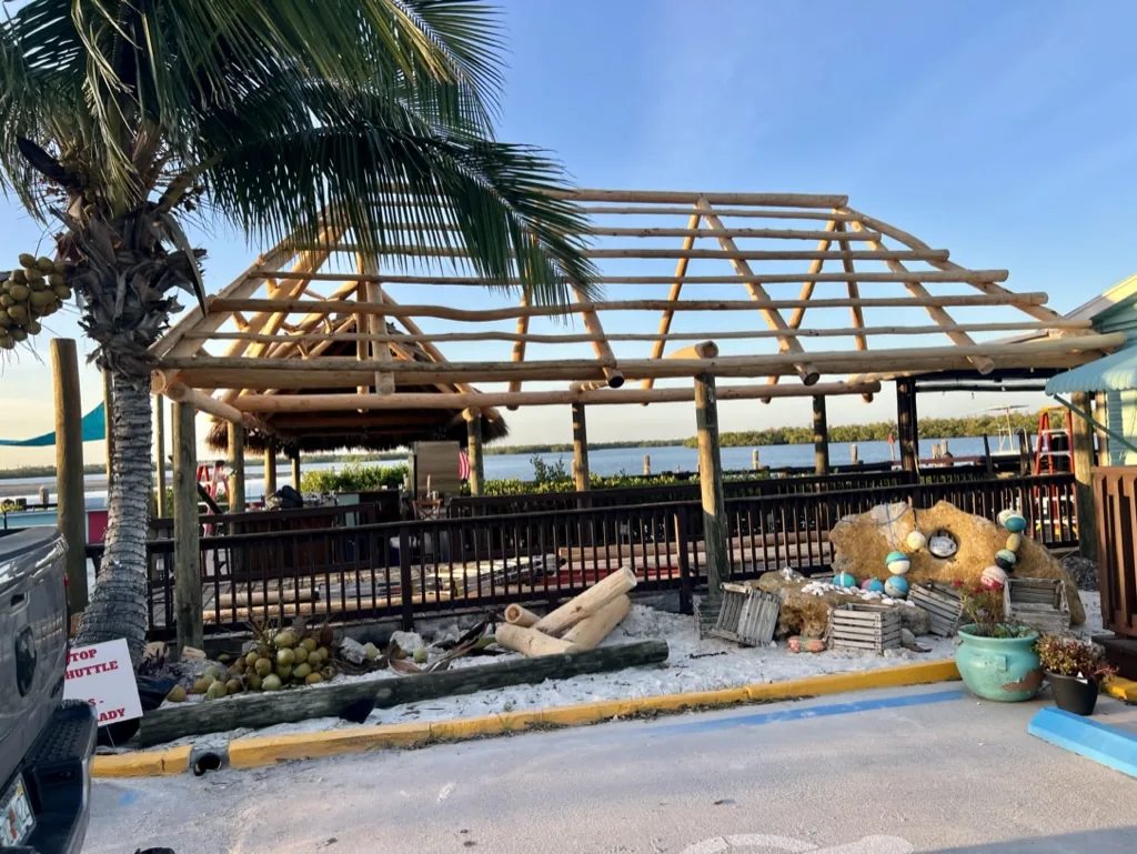 Timber tiki roof frame under construction beside a waterfront patio