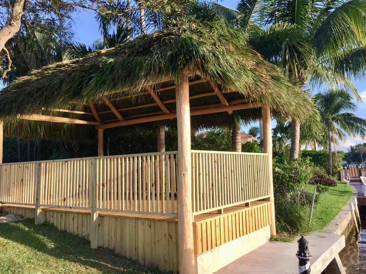Natural palm tiki hut with wooden railings beside the waterfront