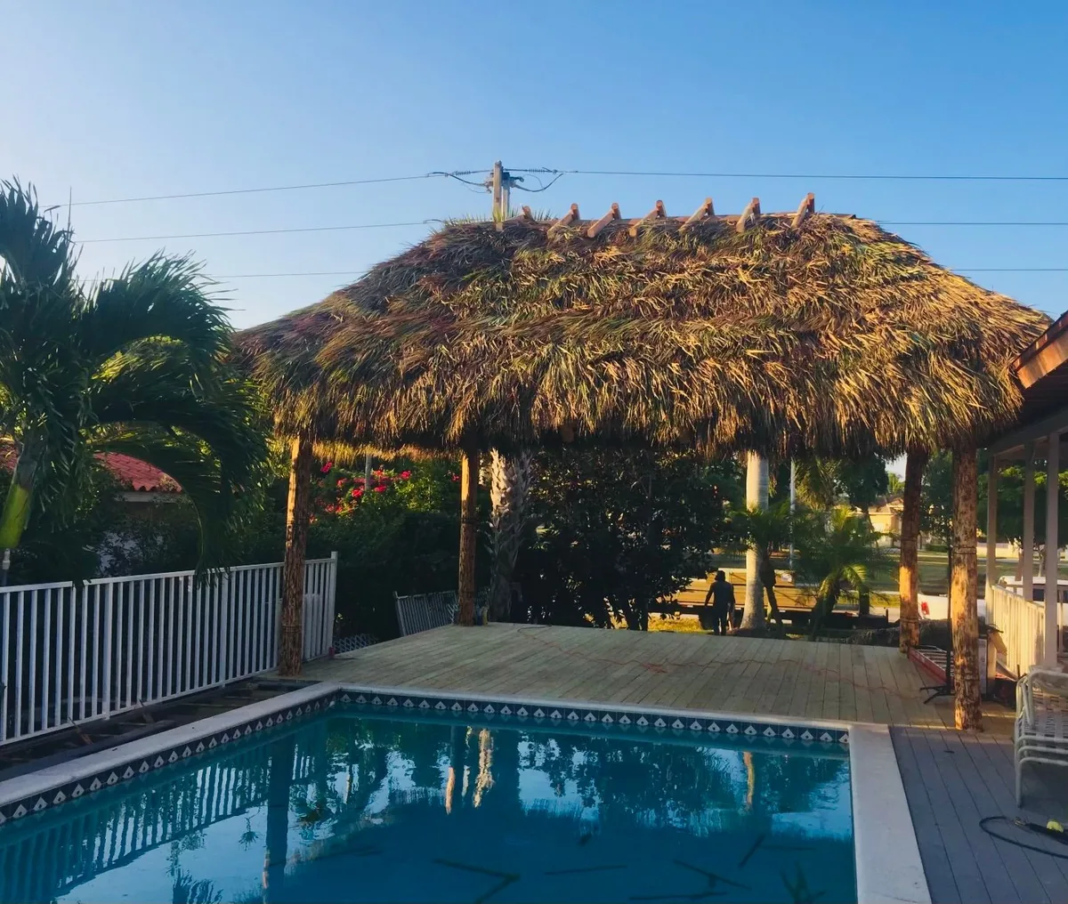 Poolside tiki hut with an outdoor dining area and wooden railings