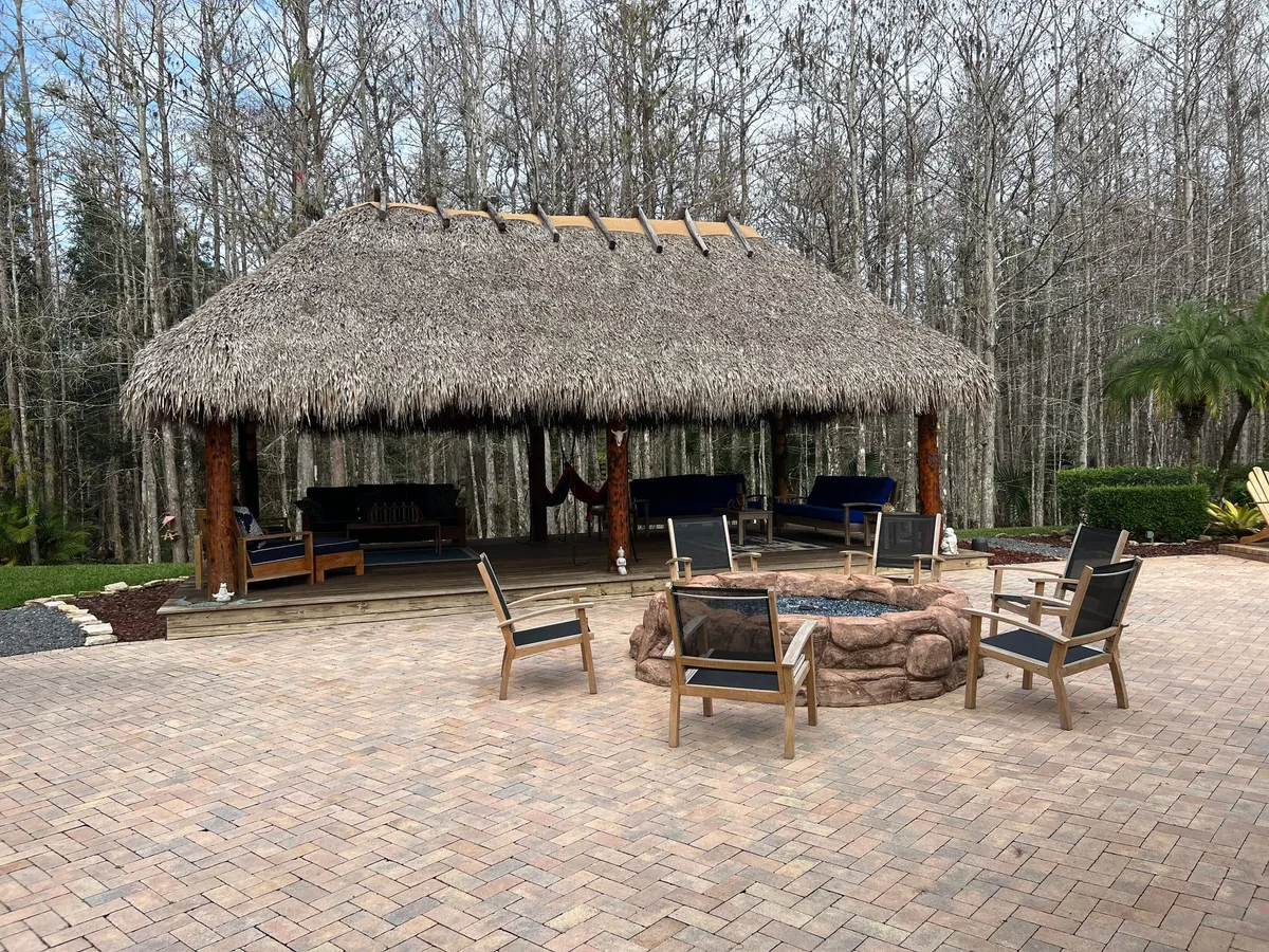 Tiki hut overlooking a paved patio with a fire pit