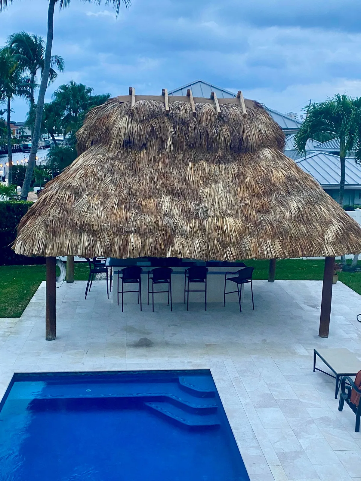 Palm-thatched tiki bar beside a swimming pool