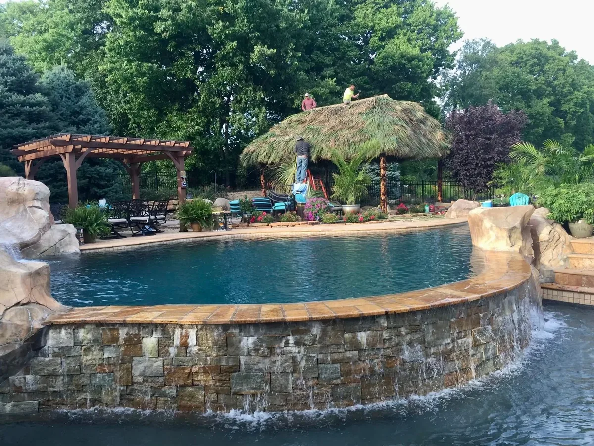 Swimming pool with a stone waterfall and a palm-thatched tiki hut