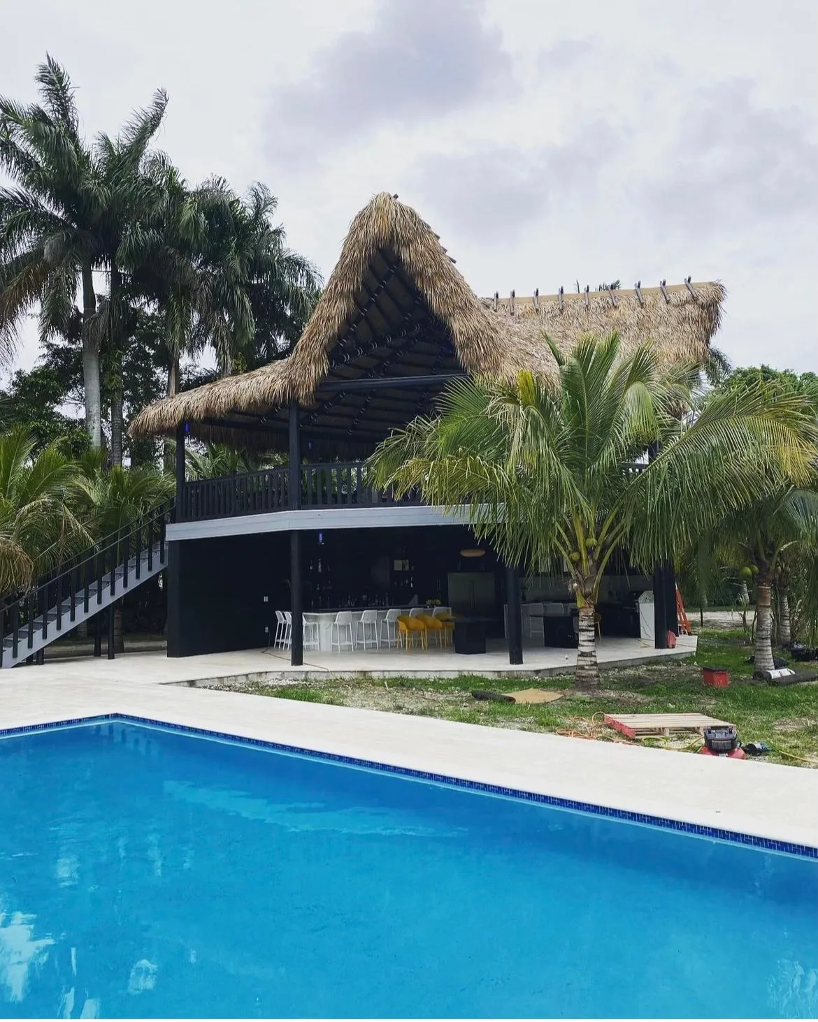 Palm-thatched tiki structure beside a swimming pool