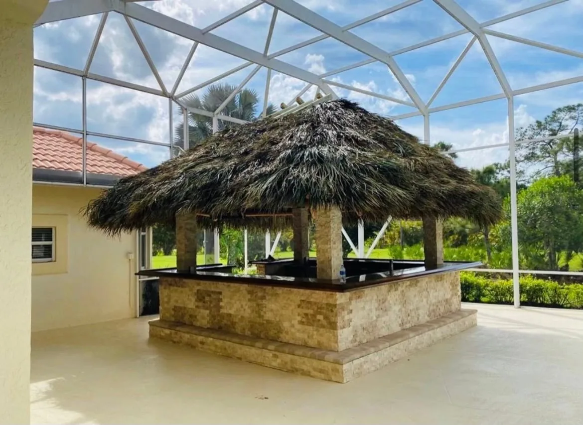 Palm-thatched tiki bar inside a screened patio