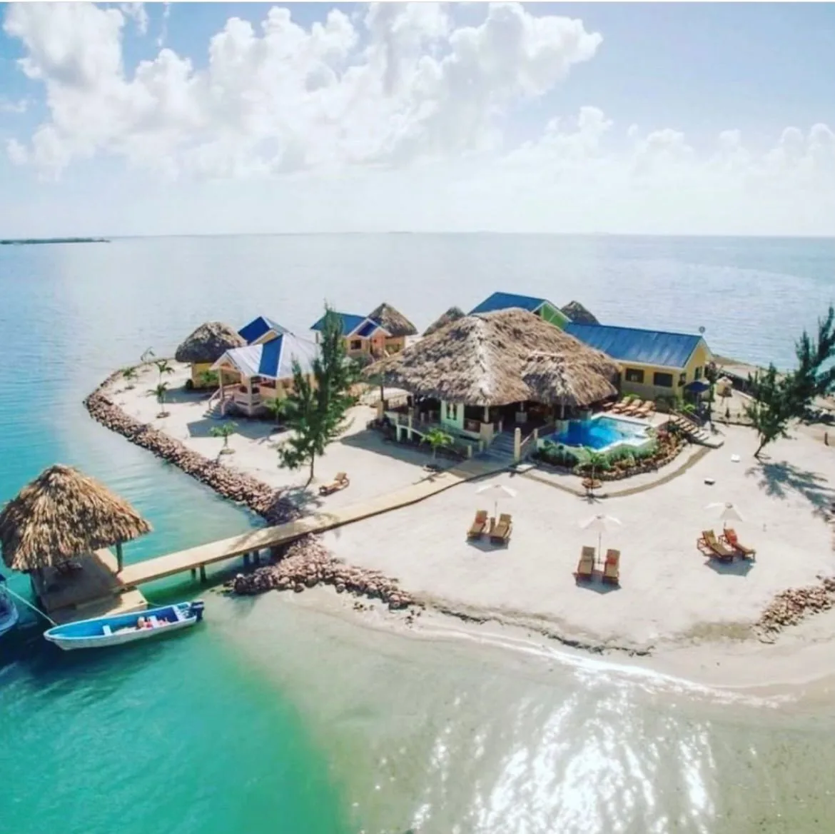 Aerial view of a waterfront island with several palm-thatched structures