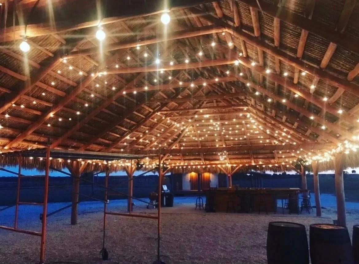 String lights suspended beneath a large tiki hut roof